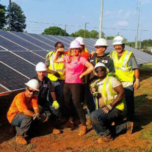 A team of workers poses next to solar panels.
