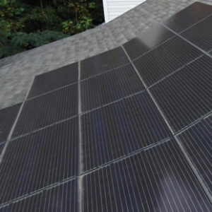 Solar panels are arranged in rows on a shingle-roofed building.