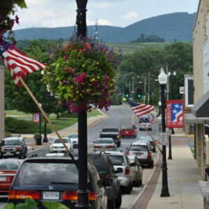 A photo showing a main street in Waynesboro, Virginia. American flags can be seen flying from flagpoles along the road.
