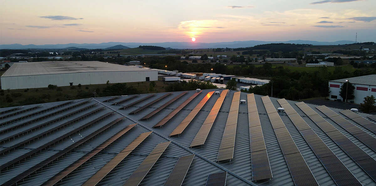 Photograph of an array of solar panels against a setting sun.