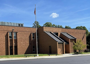 A street view of one of Calhoun County, West Virginia's public school buildings. An American flag is raised on a flagpole in front of the building's entrance.