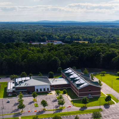 Aerial shot of a building with solar panels installed on it against a backdrop of the Blue-Ridge Mountains.