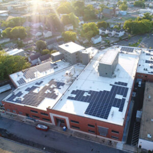 An aerial photo shows sun shining on the roof of CARITAS, a homeless shelter and recovery center in Richmond, Virginia. Solar panels can be seen on several parts of the roof.