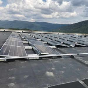 Rows of solar panels are pictured on the roof of an office building in Big Stone Gap, Virginia. The Blue Ridge Mountains are visible in the background.