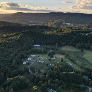 An aerial view shows a small town in the coalfield region of Virginia at sunset. Houses and farm fields are pictured, surrounded by green mountains.