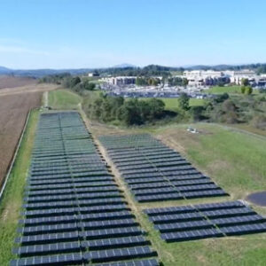 An aerial photo shows a large ground mounted solar panel array installed on farmland next to a large hospital complex in Virginia.
